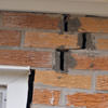A brick wall displaying stair-step cracks and messy tuckpointing on a Rutland home
