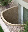 A durable plastic egress window well installed in a rock garden in Brattleboro.