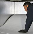 A contractor installing TerraBlock™ floor insulation in a Laconia crawl space