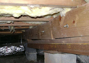A sagging crawl space with concrete supports and wooden shimming a South Woodstock crawl space