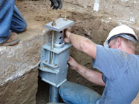 Foundation repair contractors installing the foundation bracket in Keene.