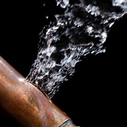A bursting copper pipe in Colchester, with water gushing out.
