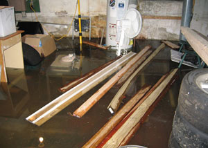 A severely flooding basement in Laconia, with lumber and personal items floating in a foot of water
